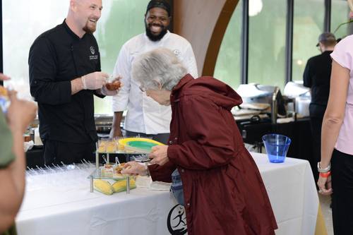 Chef offering a taste to a delighted senior guest