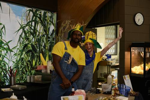 Cooking duo posing together in playful corn-husk costumes