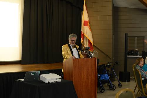 Emcee in a gold sequin jacket announcing awards