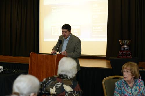 Speaker announcing the evening's total funds raised