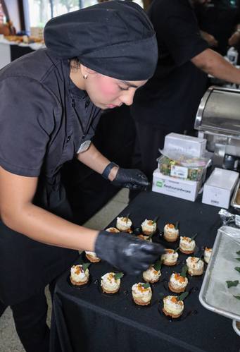 Chef in black uniform plates delicate bite-sized appetizers