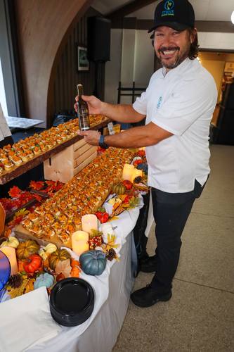 Beaming chef holds olive oil bottle beside a bruschetta spread
