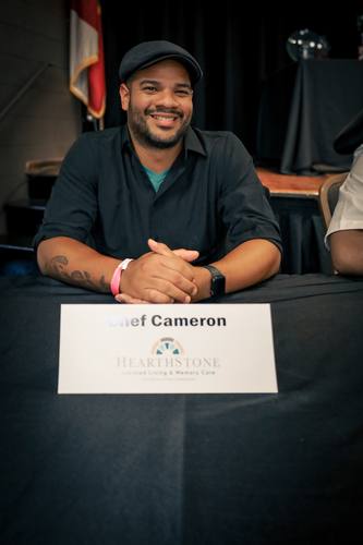 Chef Cameron of HearthStone grins at the competitors' table