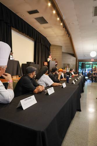 Full lineup of competing chefs seated at the judging table