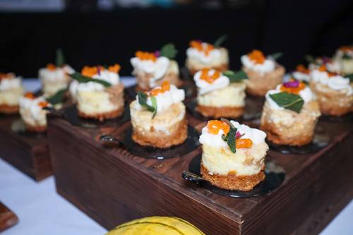 Rows of mini cheesecake bites topped with roe and sage