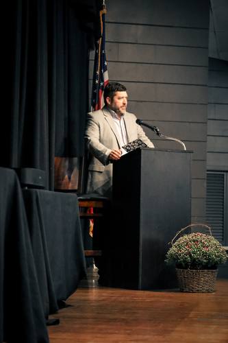 Host addresses the room from the podium