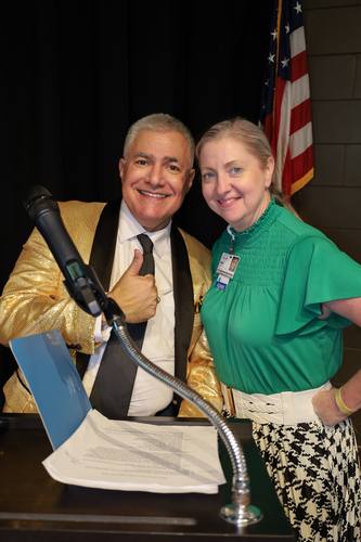 Emcee gives a thumbs up alongside a staff member